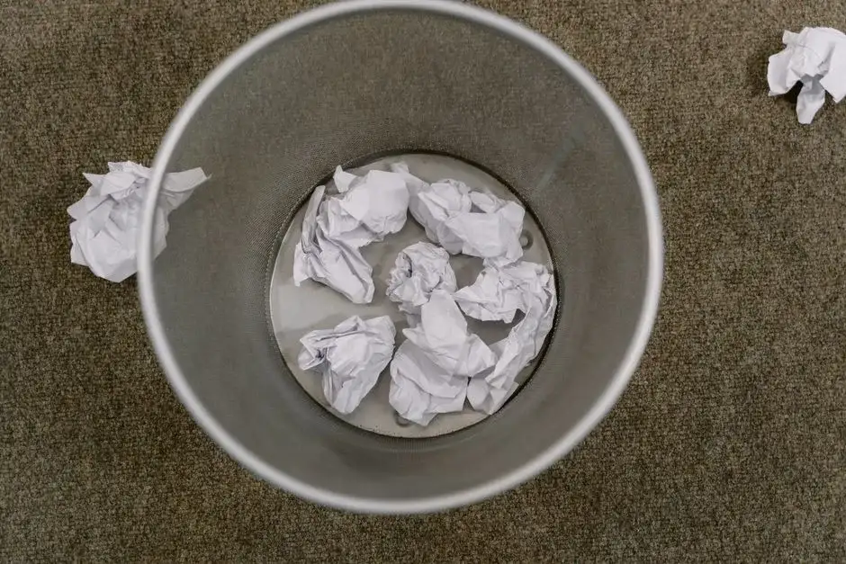 Crumpled paper being thrown in a trash bin