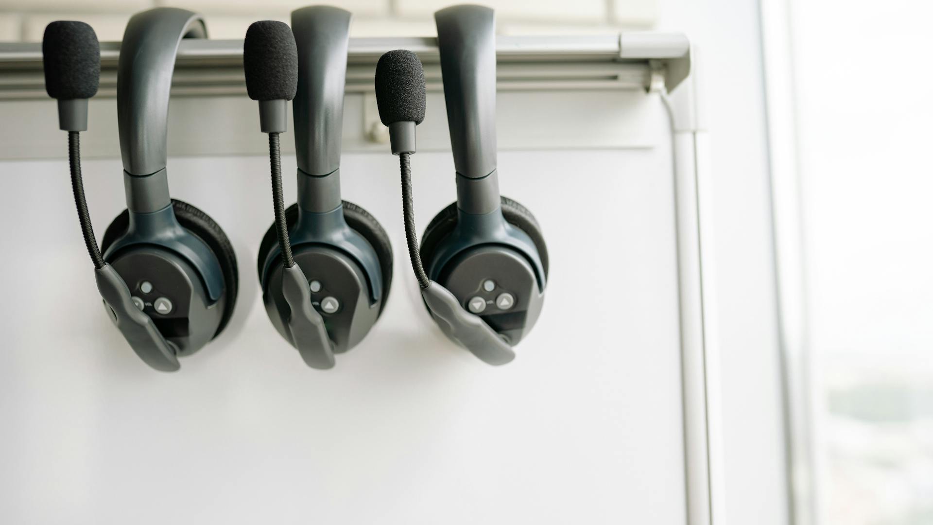 Three professional headsets organised on a hook, representing AI voice agent technology for SMBs