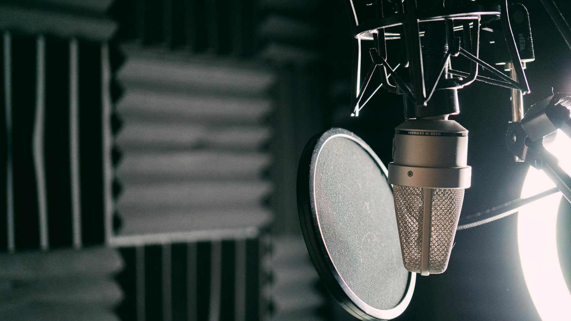 Close-up of a condenser microphone with pop filter in a professional recording studio, representing AI voice agent architecture