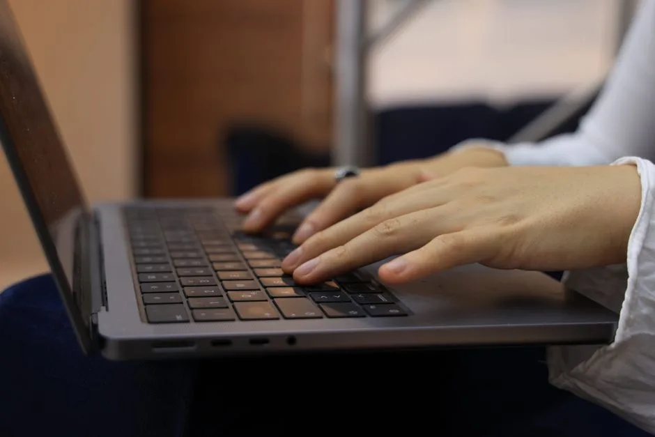 Close-up of hands typing on a laptop keyboard