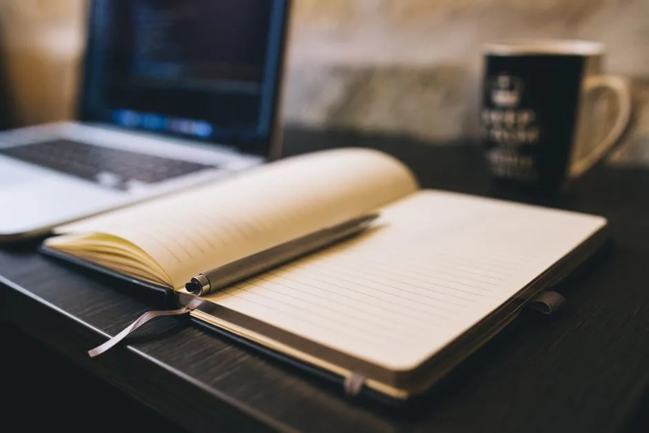 Open laptop next to a notebook on a desk
